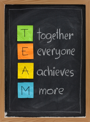 TEAM acronym (together everyone achieves more), teamwork motivation concept, color sticky notes, white chalk handwriting on blackboard